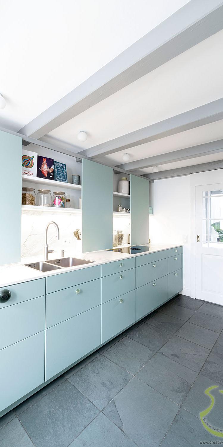 Helle moderne Küche mit mintfarbenen Schränken und grauem Fliesenboden.