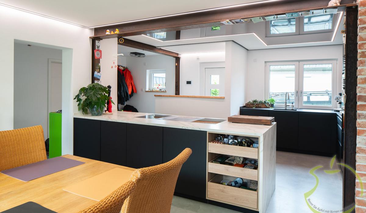 Moderne Wohnküche mit Esstisch, Kücheninsel und großen Fenstern, helle und freundliche Atmosphäre.