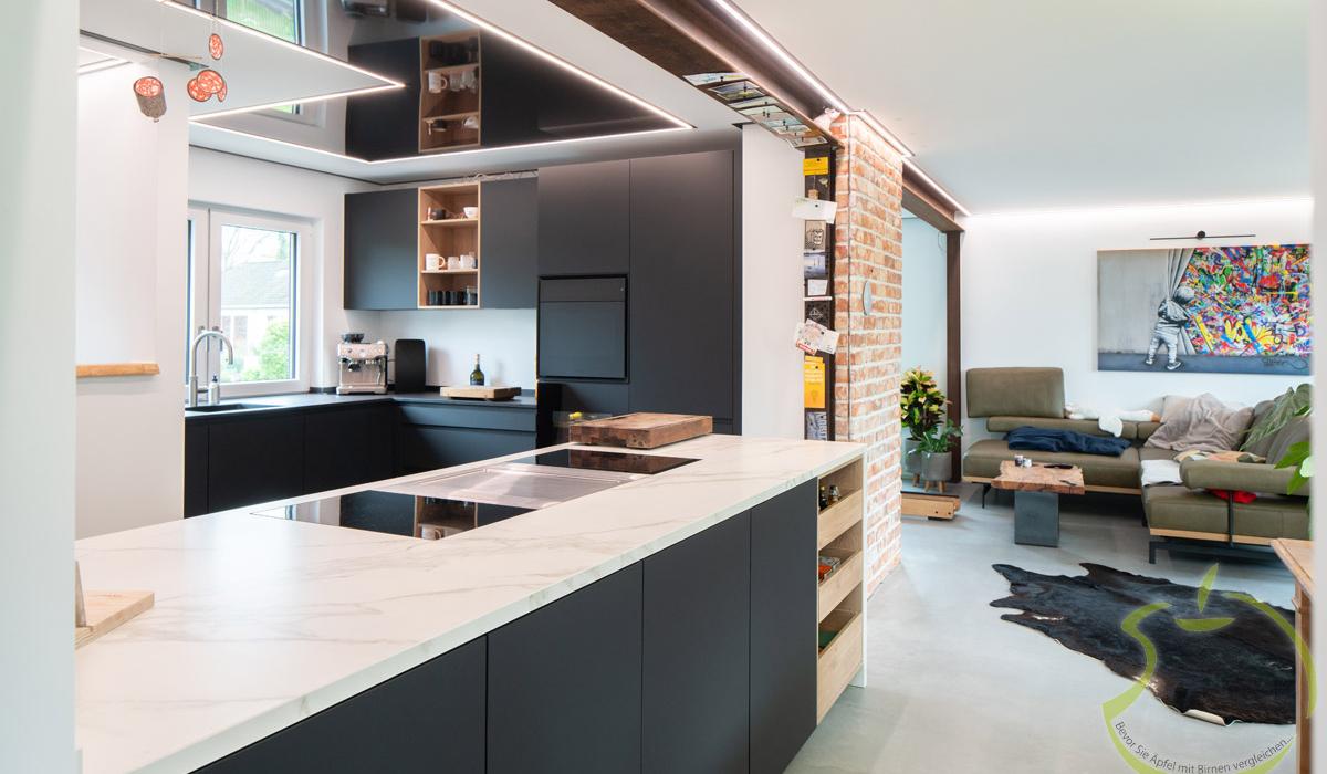 Moderne offene Küche mit dunklen Schränken und angrenzendem Wohnzimmer mit bunter Wandkunst.