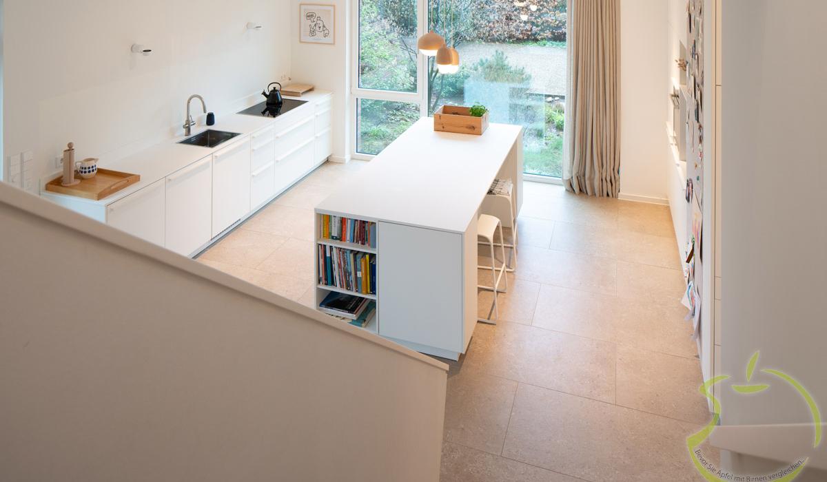 Helle, moderne Küche mit Kücheninsel und großem Fenster zum Garten.