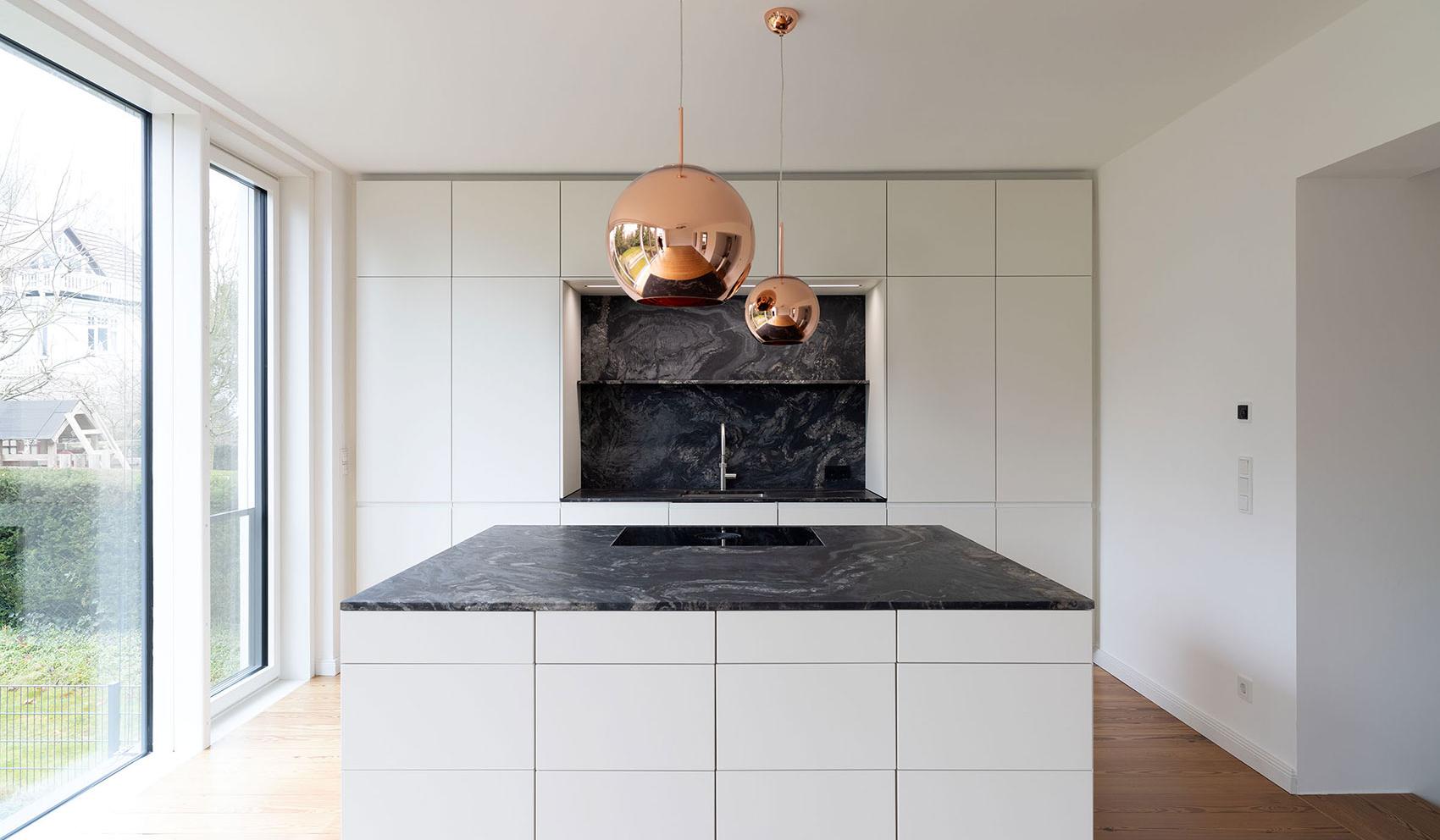 Moderne Küche mit Marmorarbeitsplatte und kupferfarbenen Hängelampen