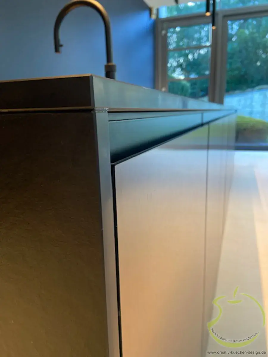 Moderne Edelstahlküchenzeile mit Wasserhahn, Fenster im Hintergrund.