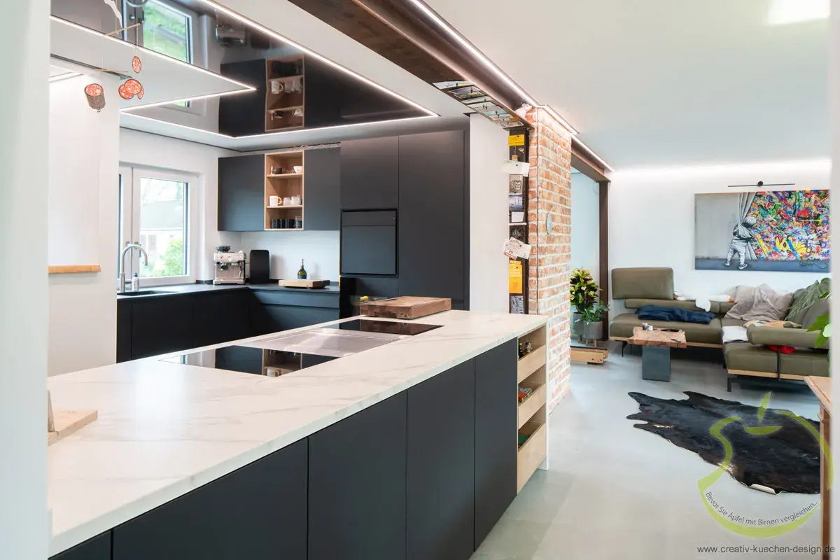 Moderne offene Küche mit dunklen Schränken und angrenzendem Wohnzimmer mit bunter Wandkunst.