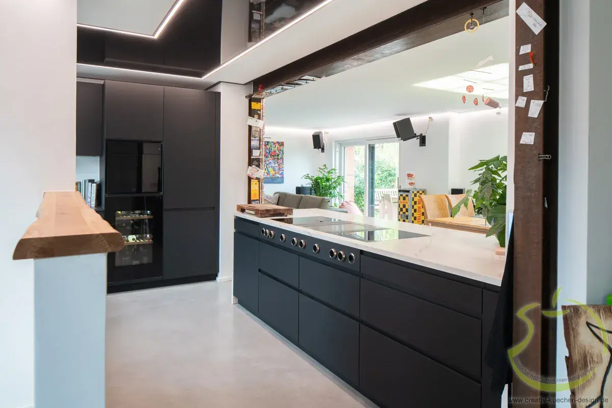 Moderne schwarze Küche mit großem Spiegel, Pflanzen und hellen Fenstern.
