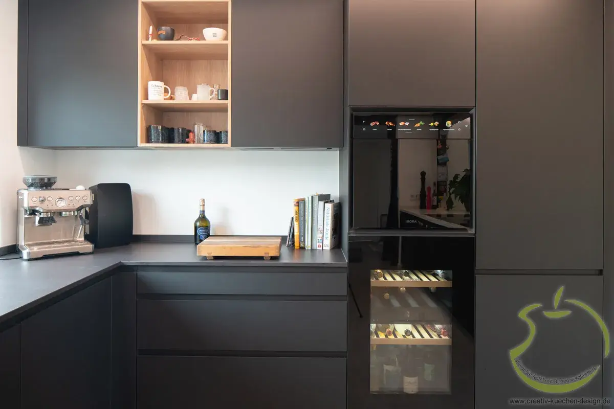 Moderne Küche mit schwarzen Schränken, Kaffeemaschine und Weinkühlschrank.