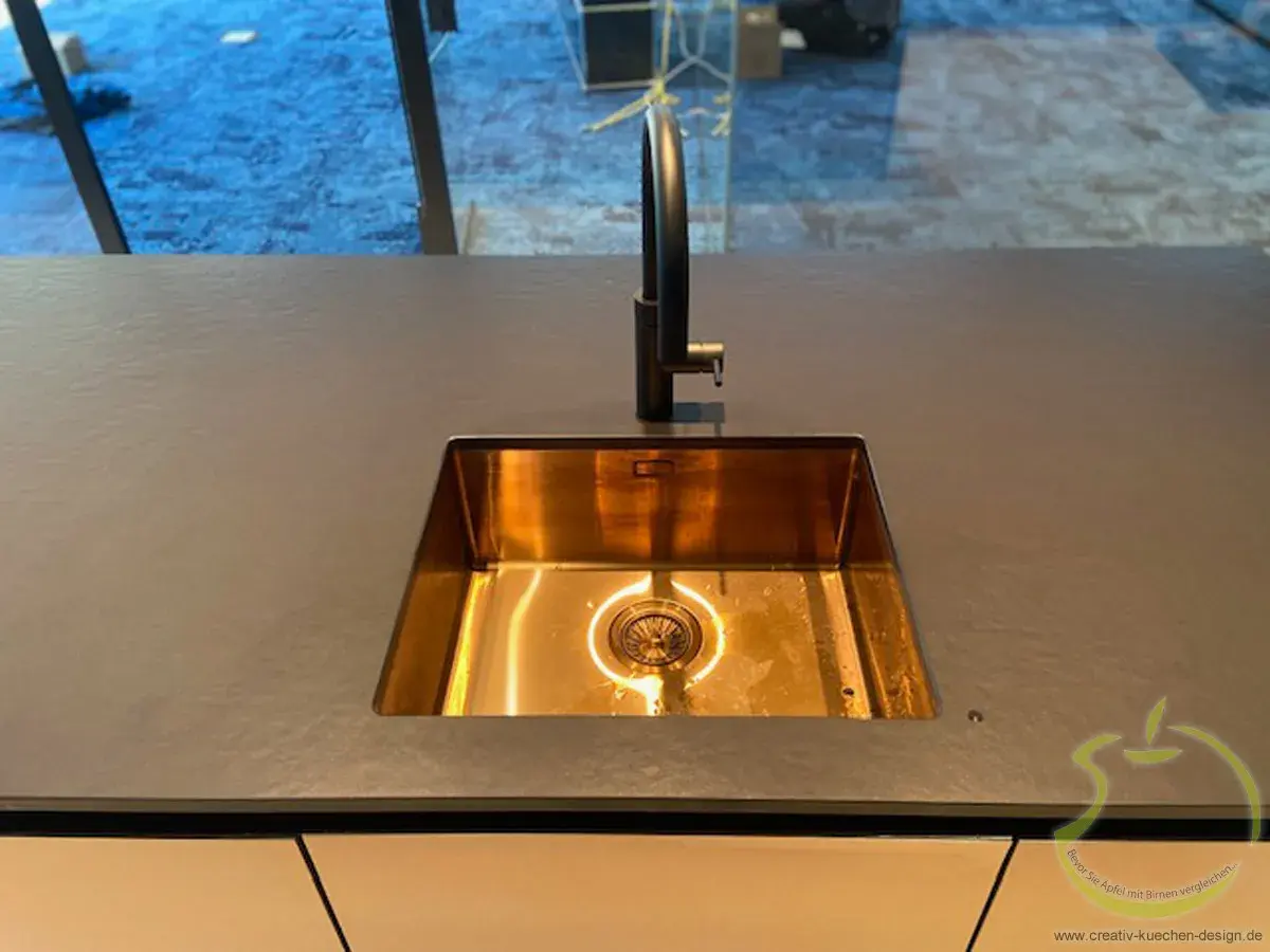 Moderne kupfergoldene Küchenspüle Unterbau mit schwarzem Wasserhahn.