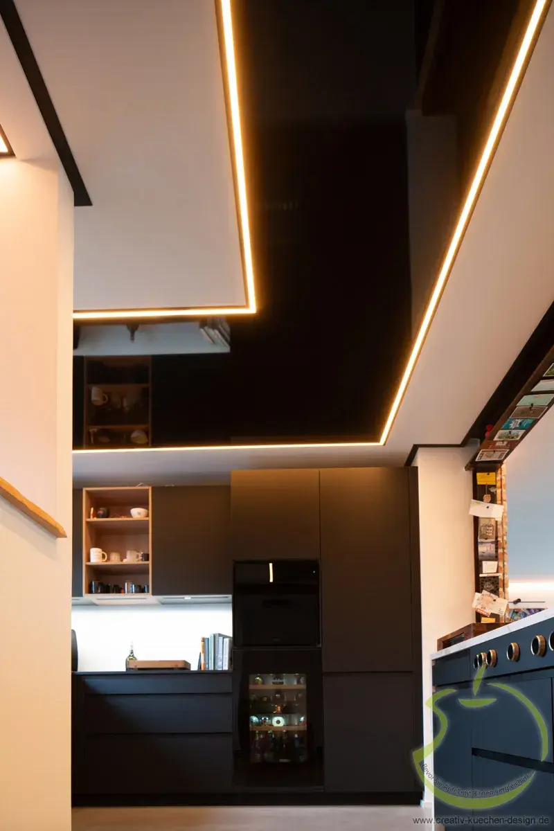 Moderne Küche mit dunklen Schränken und indirekter LED-Beleuchtung an der Decke