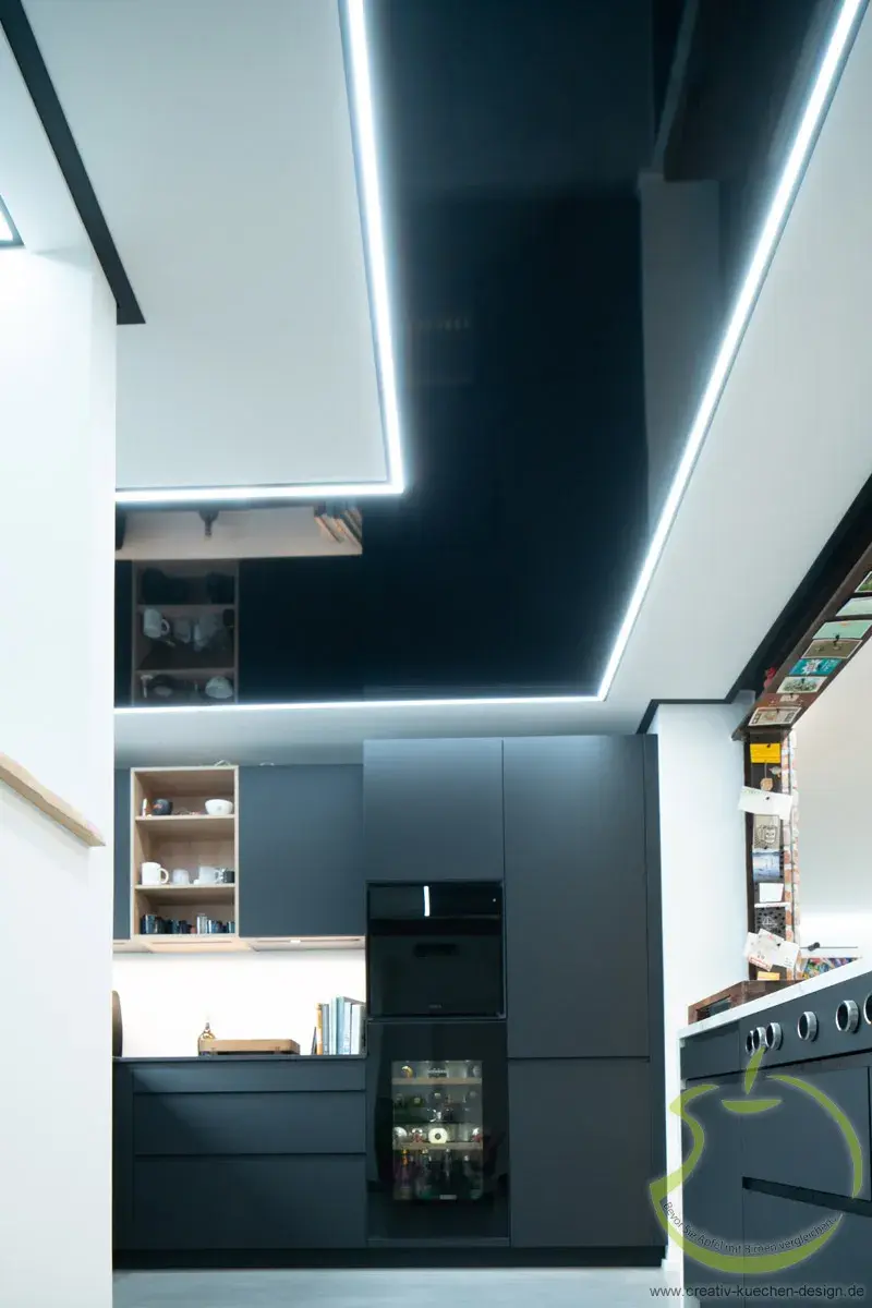 Moderne Küche mit dunklen Schränken und LED-Beleuchtung an der Decke.