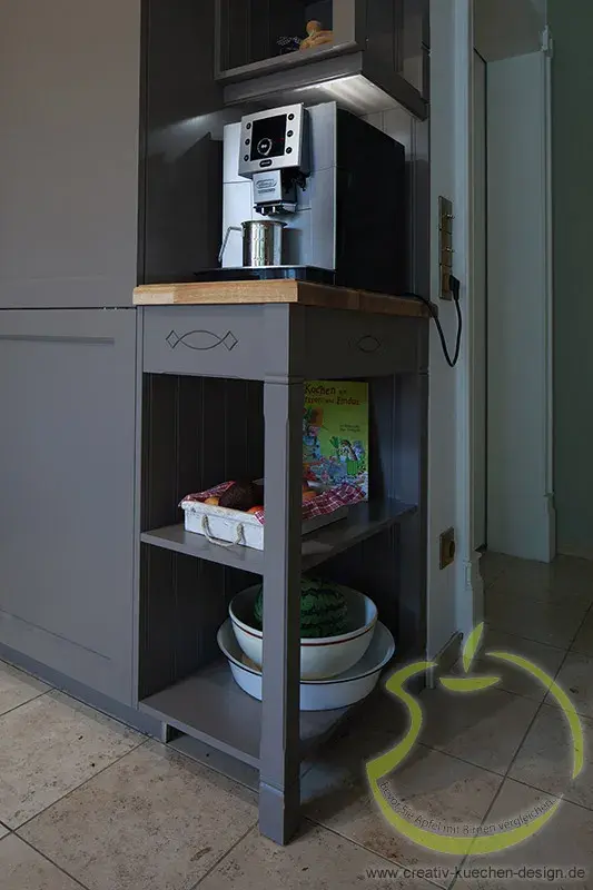 Kaffeemaschine auf grauem Küchenschrank, darunter Regale mit Schalen und Lebensmitteln.