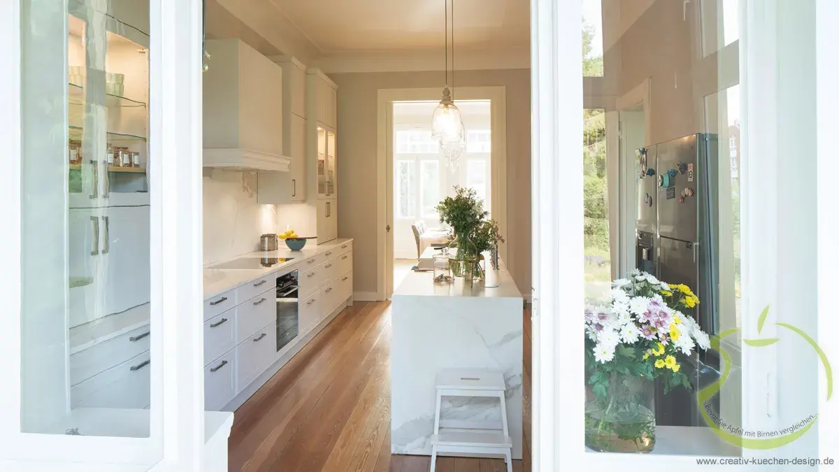 Helle, moderne Küche mit weißen Schränken und Blumen auf der Fensterbank