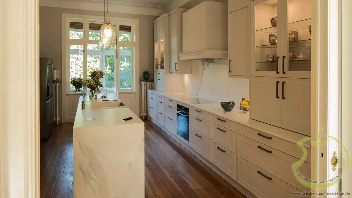 Helle, moderne Küche mit weißen Schränken, Holzfußboden und großem Fenster.