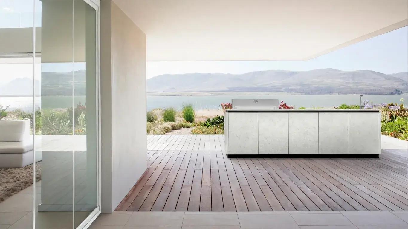 Outdoor-Küche auf großer Holzterrasse vor Landschaft mit See und Gebirge im Hintergrund