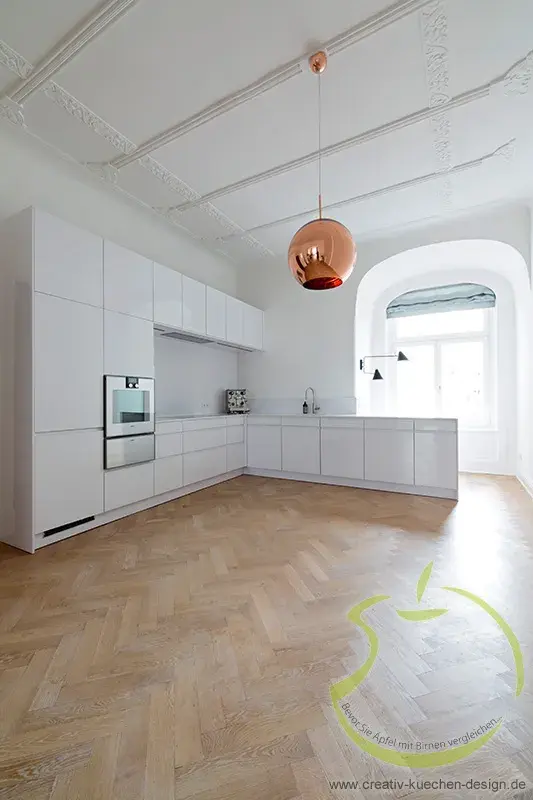 Moderne weiße Küche mit Holzfußboden, großer Fensterbogen und Kupferlampe.