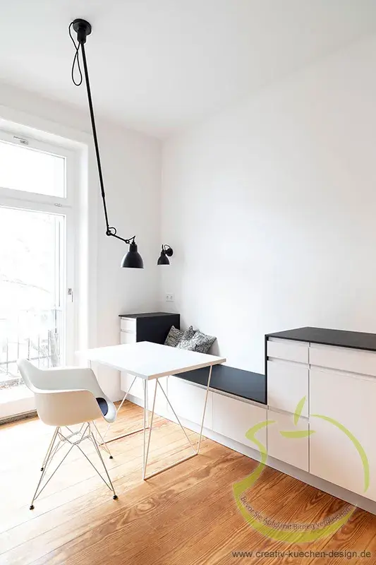Helles, modernes Esszimmer mit weißem Tisch, Stuhl und Wandleuchte.
