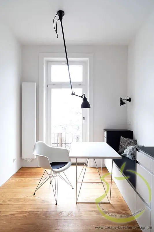 Helles, minimalistisches Arbeitszimmer mit weißem Tisch, Stuhl und großer Fensterfront.