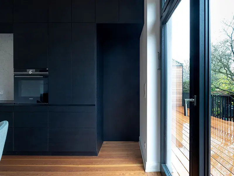 Moderne Küche mit schwarzen Schränken und großem Fenster zum Balkon