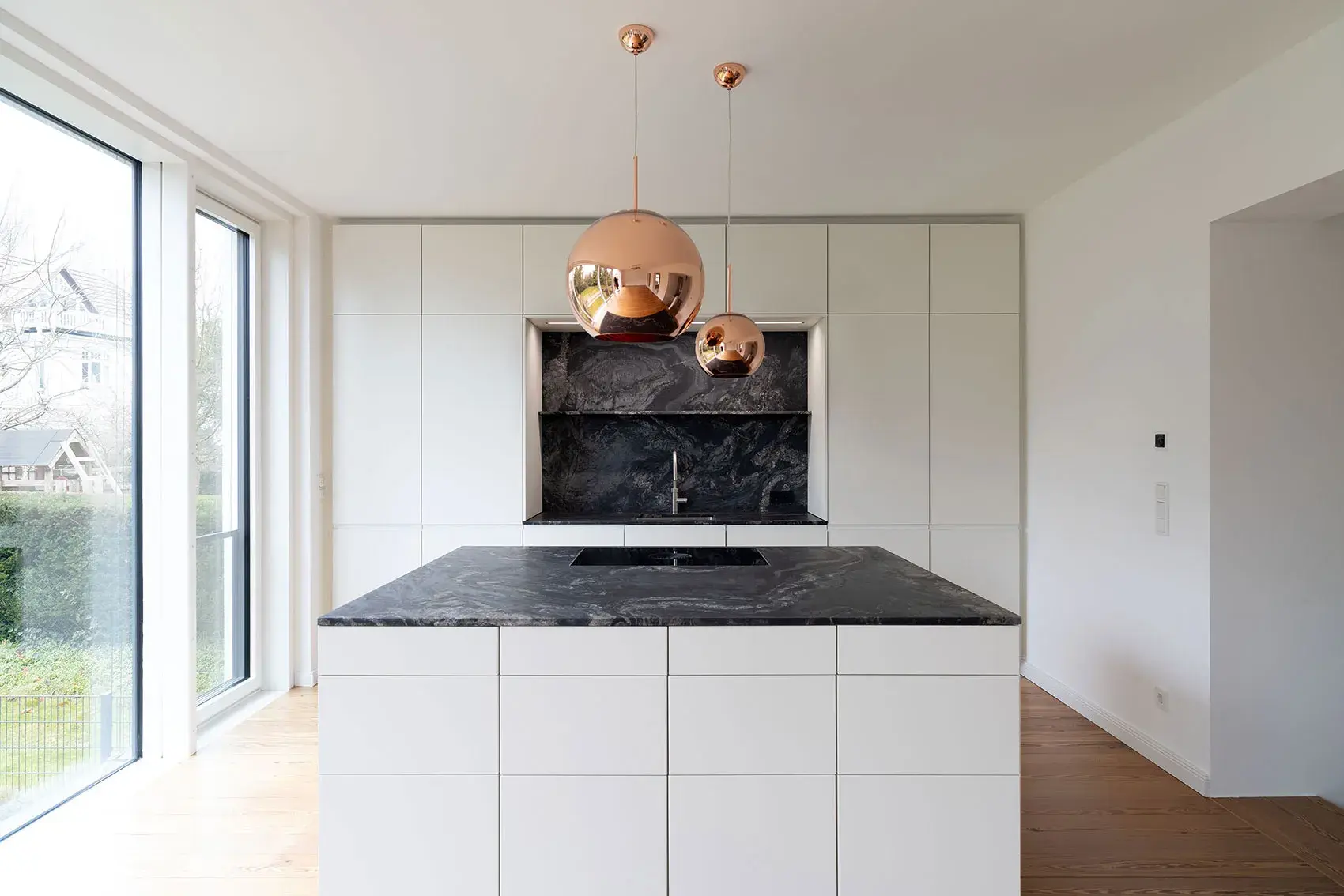 Moderne Küche mit Marmorarbeitsplatte und kupferfarbenen Hängelampen